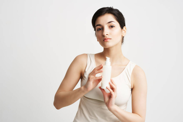 женщина в белой футболке лосьон в руках чистой косметики кожи - Фото, изображение