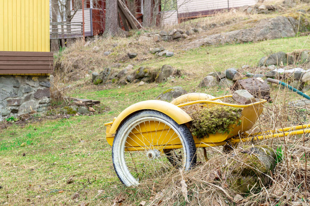 yellow garden wheelbarrow in the garden on a spring day. High quality photo - Photo, Image
