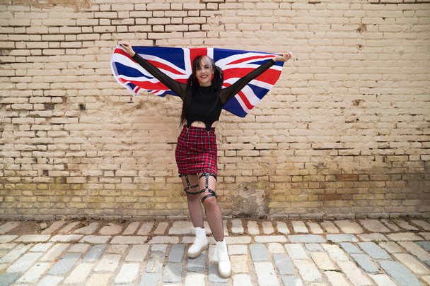 pretty young girl in punk style with the london flag on her shoulders celebrating some national event. Patriotic concept. - Foto, Imagem