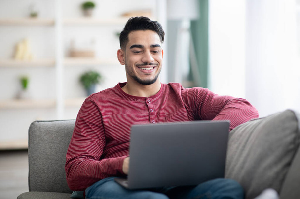 Positive arab guy surfing on social media, using laptop - Foto, immagini