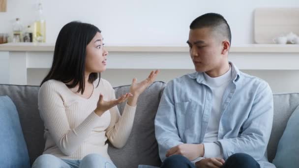 Asiática pareja having quarrel sentado en sofá en casa - Metraje, vídeo
