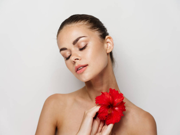 目を閉じて赤い花を持つ女性  - 写真・画像