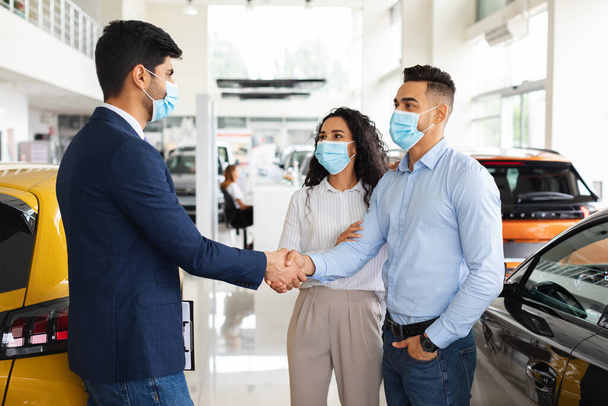 Middle-eastern couple shaking salesman hand, buying new car - Photo, Image