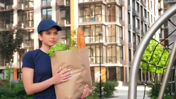 Voedsel levering vrouw koerier met papieren zak boodschappen om bestelling klant te leveren - Video
