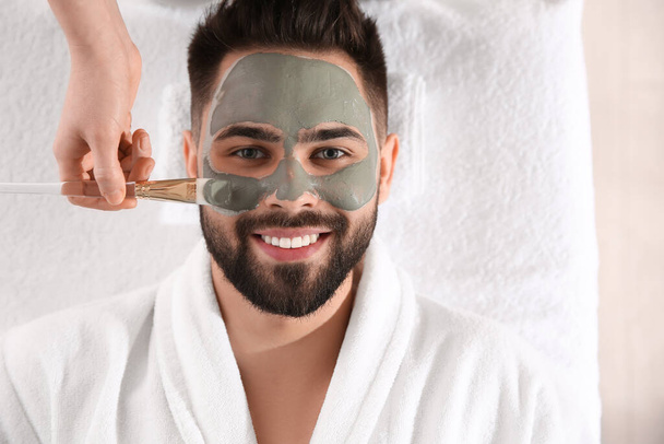 Cosmetologist applying mask on man's face in spa salon, top view - Foto, imagen