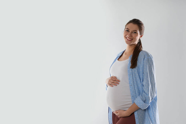 Happy young pregnant woman on white background, space for text - Fotografie, Obrázek