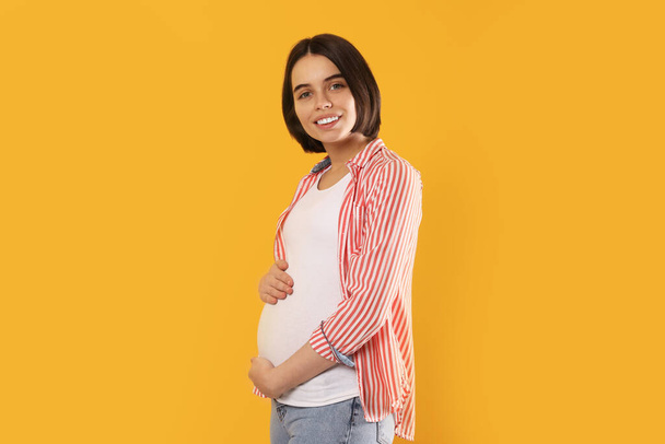 Happy young pregnant woman on yellow background - Fotoğraf, Görsel