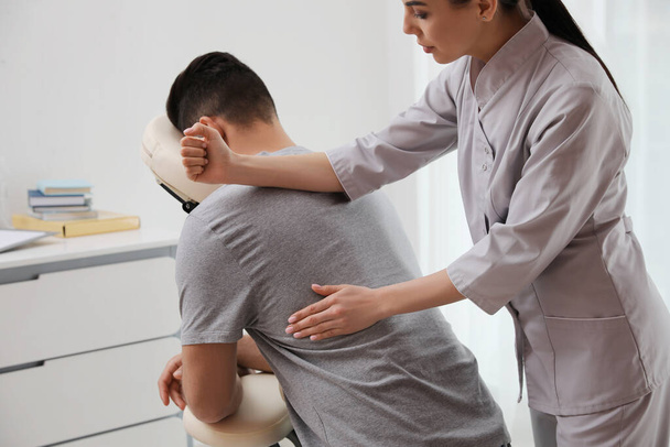 Man ontvangt massage in moderne stoel binnen - Foto, afbeelding
