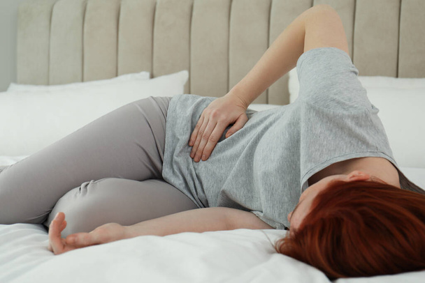 Woman suffering from appendicitis inflammation on bed at home - Φωτογραφία, εικόνα