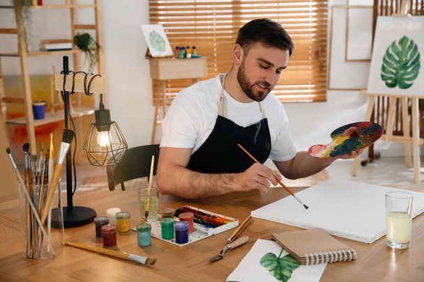 Young man painting with brush in artist studio - Valokuva, kuva