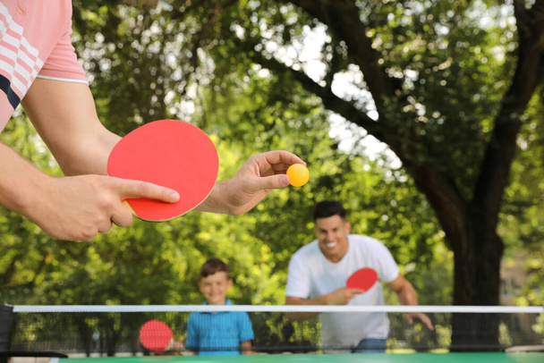 Family with child playing ping pong in park, closeup - Фото, зображення