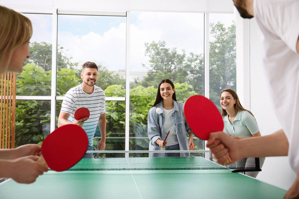 Happy friends playing ping pong together indoors - Foto, afbeelding