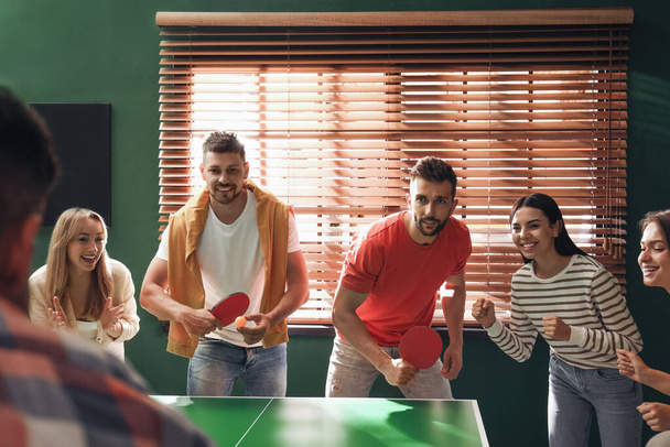 Happy friends playing ping pong together indoors - Foto, Imagen