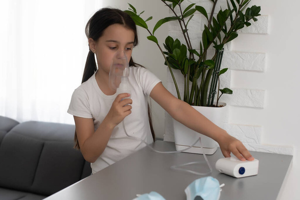 Egy kislány belélegzi a porlasztót otthon. gyermek asztma inhalátor inhalációs porlasztó gőz beteg köhögés koncepció. - Fotó, kép