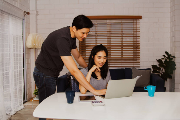 Coppie asiatiche lavorano online insieme per discutere i documenti commerciali online e fare il loro lavoro a casa sul proprio laptop. Guarda il laptop: le coppie pianificano il loro business e lavorano da casa.. - Foto, immagini