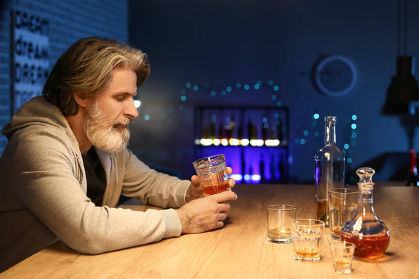Senior man with glass of drink late in evening at home - Photo, Image
