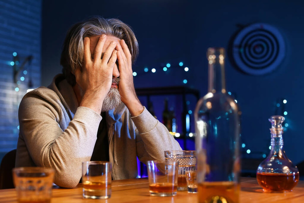 П'яний старший чоловік сидить за столом у барі
 - Фото, зображення