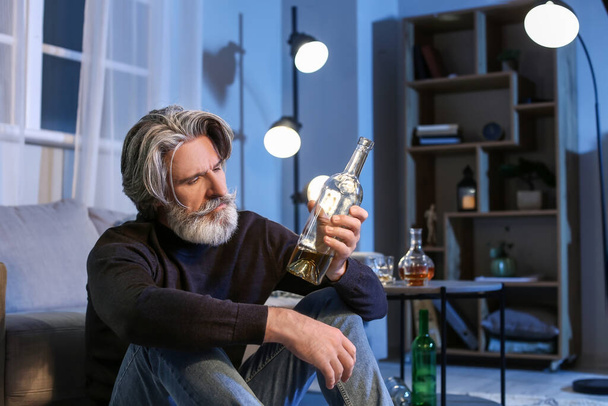 Uomo anziano con bottiglia di bevanda a tarda sera a casa - Foto, immagini
