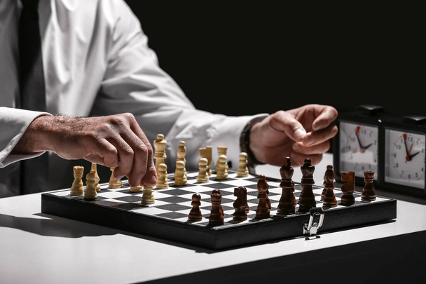 Senior man playing chess on dark background, closeup - Фото, зображення