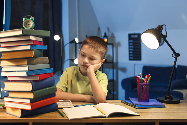 Little boy tired of doing homework at home late in evening - 写真・画像
