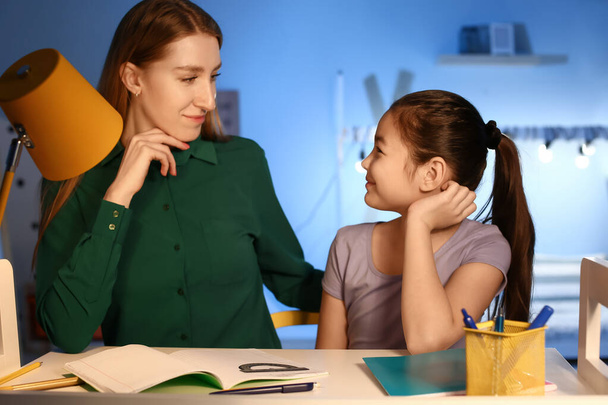 Little girl with her mother doing homework at home late in evening - Photo, Image