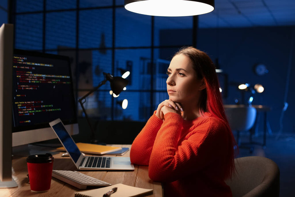 Programadora femenina trabajando con computadora en la oficina por la noche - Foto, imagen