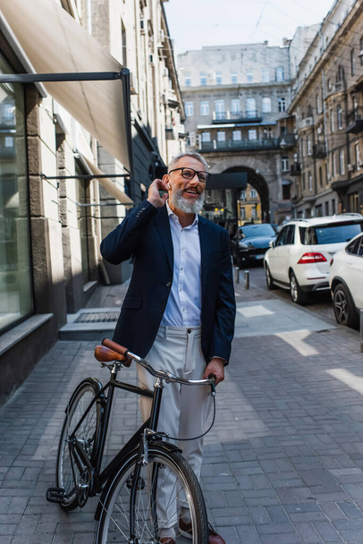 щасливий зрілий чоловік слухає музику в навушниках біля велосипеда
  - Фото, зображення