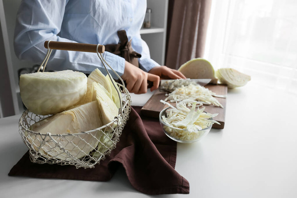 Женщина режет свежую капусту на столе на кухне, крупным планом - Фото, изображение