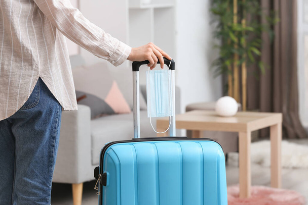Жінка з упакованою валізою та медичною маскою вдома
 - Фото, зображення