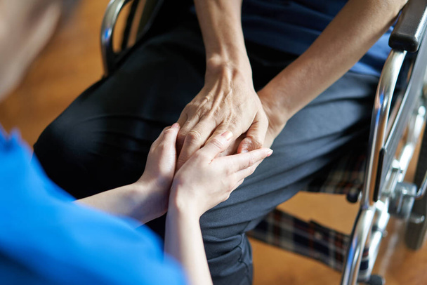 Hands of elderly people in wheelchairs and caregivers - Foto, imagen