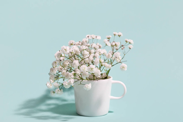 Cup with beautiful gypsophila flowers on color background - Foto, Imagen