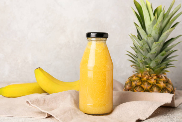 Bottle of tasty pineapple smoothie on light background - Photo, Image