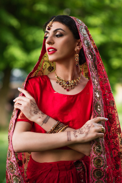 young indian bride in red sari and headscarf with ornament  - Фото, зображення