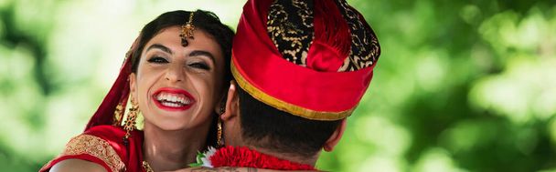 Rückseite des indischen Mannes im Turban umarmt glückliche Braut mit traditionellem Kopftuch, Banner - Foto, Bild