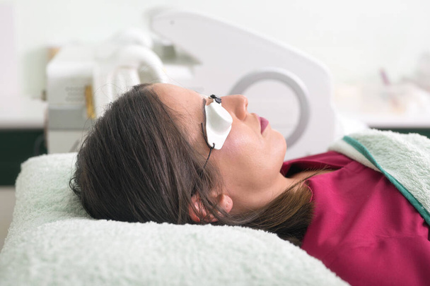 woman lying with protection glasses in beauty salon. - Photo, Image