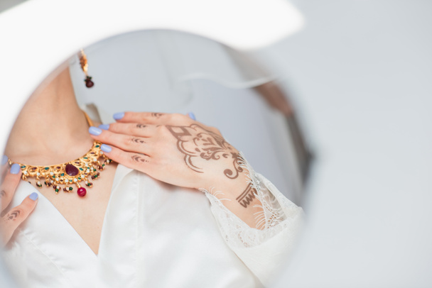 イヤリングの若いインドの花嫁の鏡に映る白いネックレスを身に着けて - 写真・画像