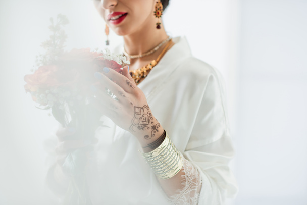 cropped view of indian bride holding bouquet of flowers on white - Photo, Image