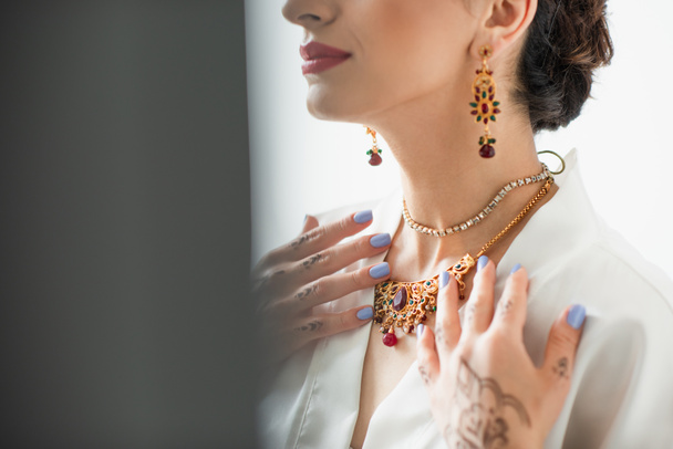abgeschnittene Ansicht der indischen Braut, die Halskette auf Weiß berührt - Foto, Bild