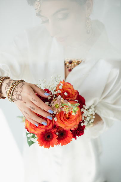 giovane sposa indiana con mehndi che tiene fiori su bianco - Foto, immagini
