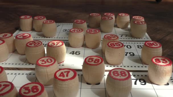 Tradiční ruské lotto. Karty s čísly, detailní záběr. Dřevěné sudy s čísly na bílém pozadí. Hráč dává dřevěné sudy na karty s odhadovanými čísly - Záběry, video