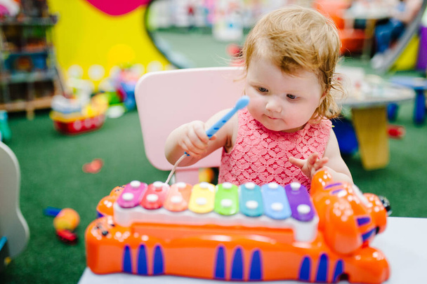 Happy little kid, baby girl 1-2 years plays a musical instrument xylophone in game center, amusement of the children's room for birthday. indoor entertainment. - Fotó, kép