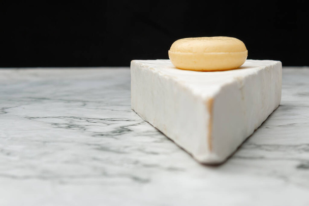 Zbliżenie wizerunek białego akawi sera z okrągłym pokrojonym małym serem na tym na marmurowej powierzchni - Zdjęcie, obraz