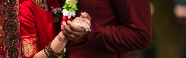 cropped view of indian man holding hands with bride with mehndi in sari, banner - Foto, immagini