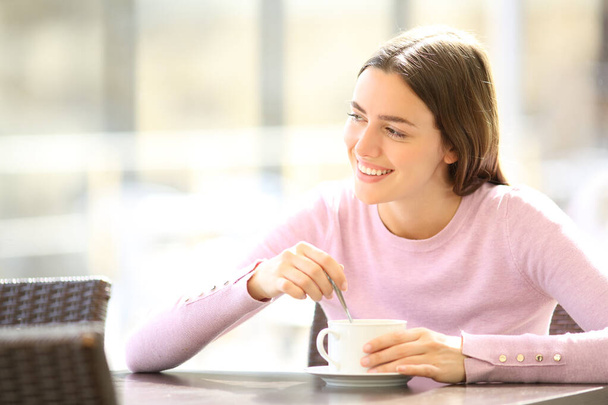 Happy woman stirring coffee sitting in a restaurant terrace - Fotografie, Obrázek