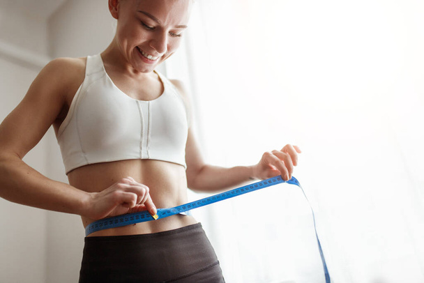 Slim woman measuring waist with tape - Photo, Image