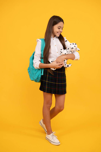 幸せな子供でバックパックとおもちゃで学校の制服長さで黄色の背景,学校の時間 - 写真・画像