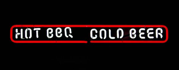 A glowing white sign saying "hot BBQ" and "cold beer" with a red outline on a pitch-black background - Zdjęcie, obraz