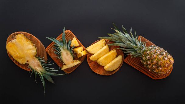 Sliced pineapple in different shapes. Ripe pineapple on cutting board cooking summer dessert on black background. Flat lay. Long web banner - Foto, Bild