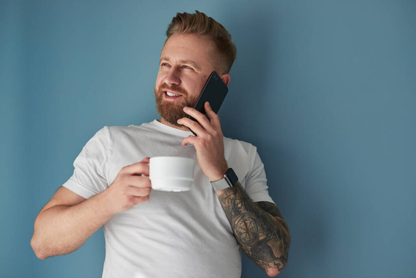 Man with hot drink speaking on smartphone - Photo, Image