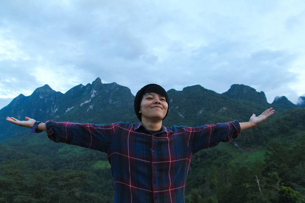 Aasialainen nuori mies Skotlannin paita ja musta hattu vaellus avoin käsi onnellinen vuoren huipulla pilvien yläpuolella ja sumu Patikointi ulkona. Doi Luang Chiang Dao Chiangmain maakunta, aamulla. - Valokuva, kuva